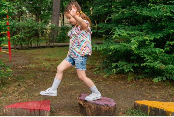 child balancing on wooden stump from one stump to the other